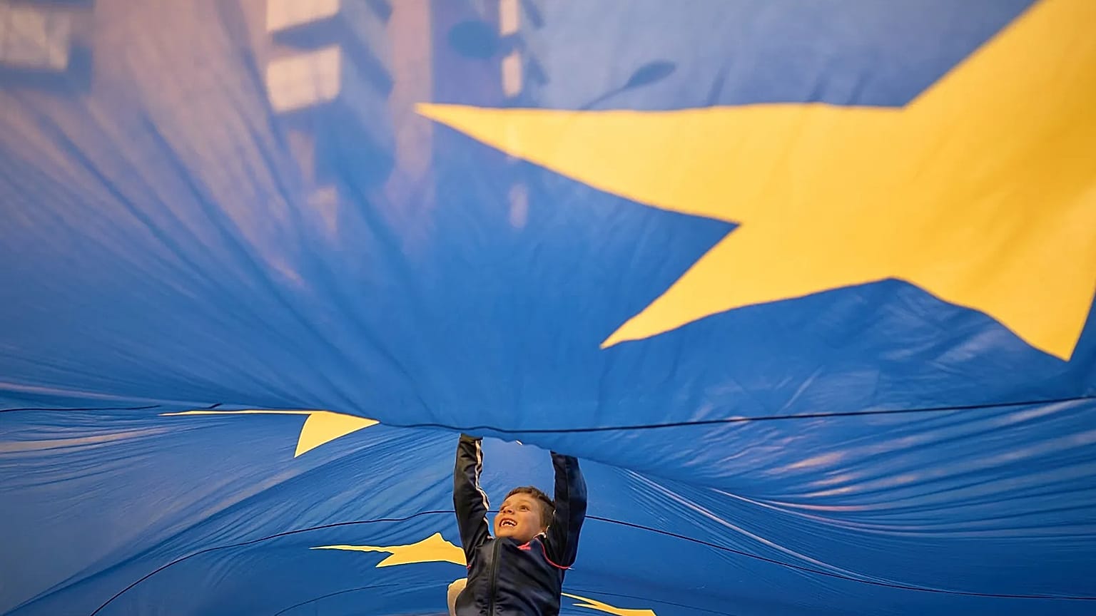 FILE - A child jumps under an European Union flag during a pro-EU rally ahead of the second round of the presidential election in Bucharest, Romania. May 2025