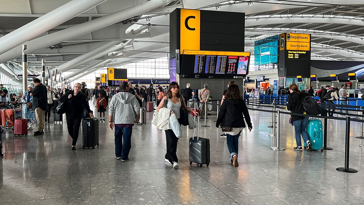 Passengers walk past the departures board at Heathrow Airport, in London, 28 August 2023.