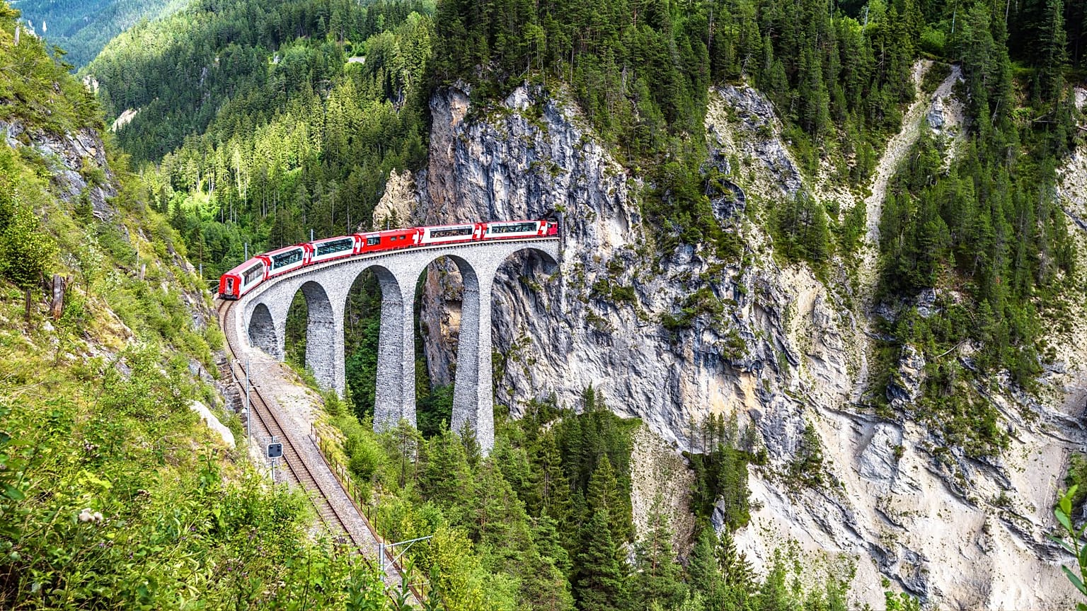 Aerial view of a railway bridge and red train in Switzerland. 
