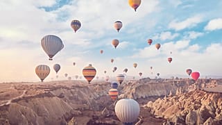 Hot air balloons, carrying tourists, rise into the sky above the "fairy chimneys" in Cappadocia, central Türkiye.