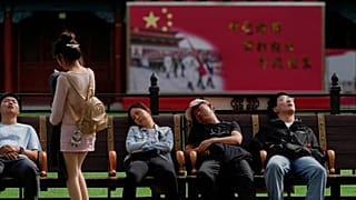 FILE - Tourists nap outside a barrack for honor guards near the Forbidden City during the National Day holidays in Beijing, Wednesday, Oct. 1, 2025.