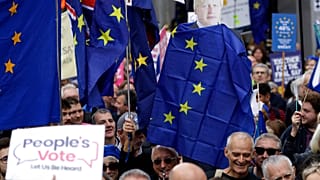 FILE - Anti-Brexit remain in the European Union supporters hold with former Prime Minister Boris Johnson draped in an EU flag as they demand another Brexit vote. 2019 