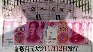 In this Aug. 11, 2015 photo, a shadow of a man is reflected on a glass as he reads a newspaper reporting China's central bank, the People's Bank of China.