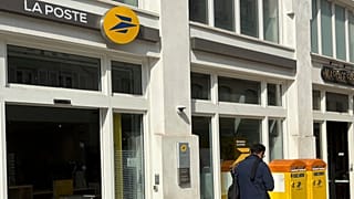 FILE: A man walks past an office of France's national postal service, La Poste in Paris, 26 August 2025
